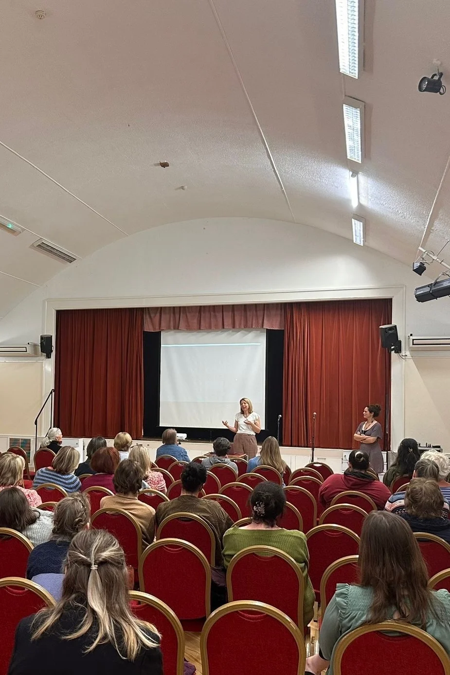 Dr Rebecca Hiscutt PhD speaking to a full hall at an NHS metabolic health roadshow